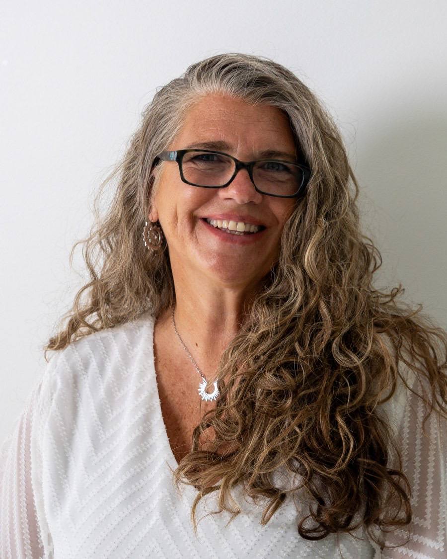 Smiling portrait in a white knit top, glasses, soft daylight